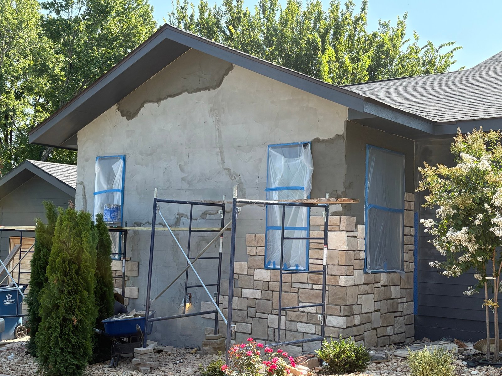 Stucco base coat and stone veneer installation on the same wall