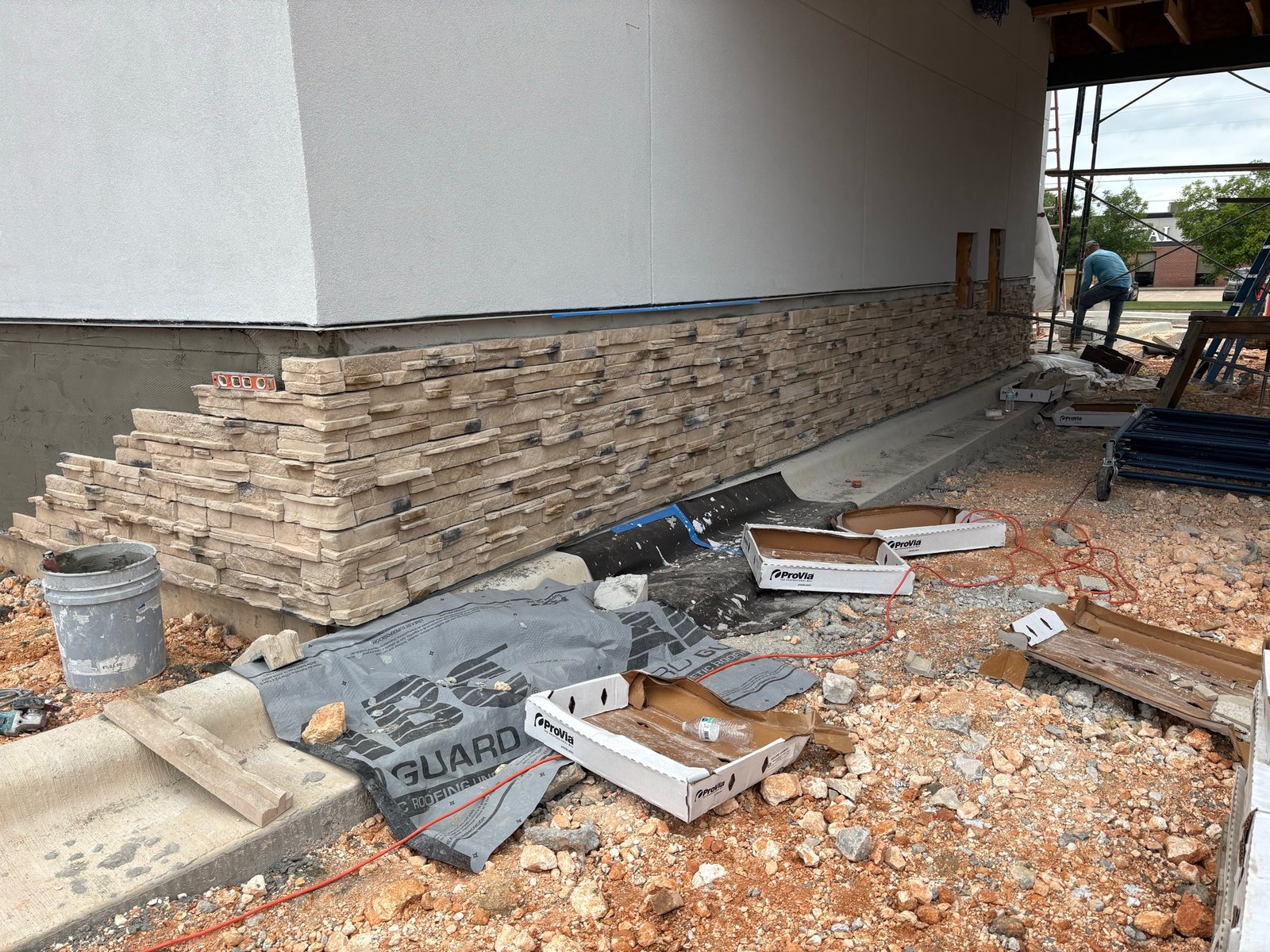 Stone veneer wainscot installation on a stucco building