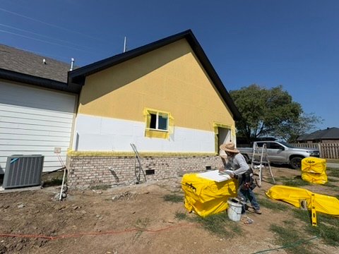 Crew member applying stucco base coat at a gable end